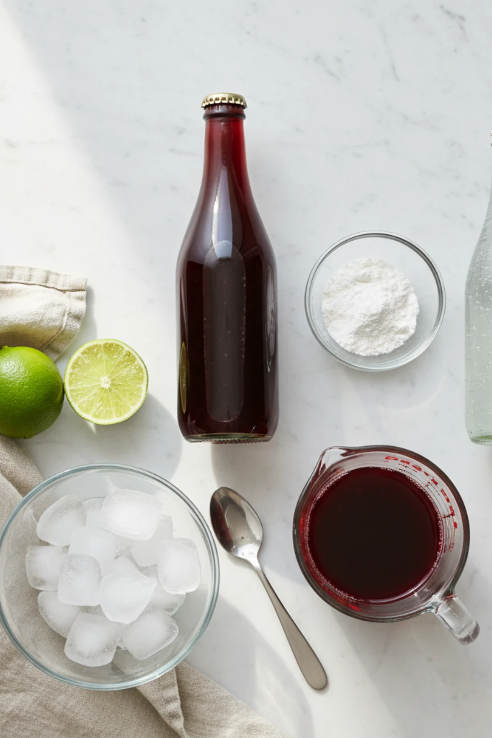 Close-up top-down view of Sleepy Girl Mocktail ingredients: tart cherry juice, magnesium powder, and fresh lime, arranged on marble surface with natural wear, looking home-prepared and fresh.